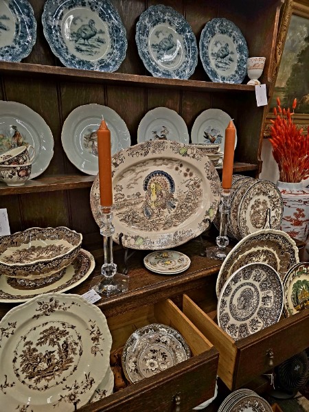 Brown English transferware platters and plates staged on an oak dresser with candlesticks