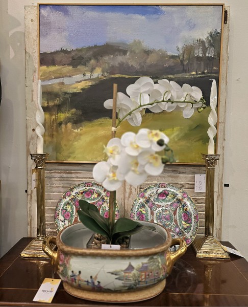 A white orchid planted in a famille rose Chinese footbath between brass candlesticks