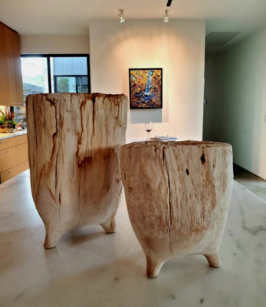Two carved wood pedestal tables on a marble floor in a modern kitchen