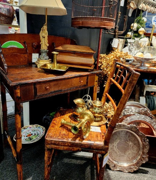 An antique bamboo desk styled with brass candlesticks, a carved figure and silver trays